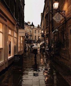 a person walking down a wet street in the rain with an umbrella over their head