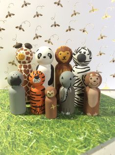 a group of wooden toy animals standing next to each other on grass with bees in the background