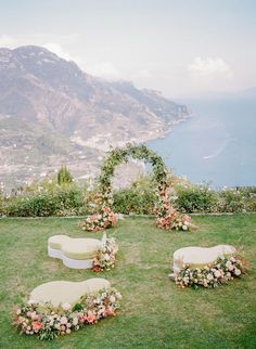 an outdoor ceremony setup with flowers and greenery on the lawn, overlooking the ocean