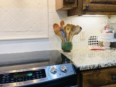 a kitchen counter with utensils in a vase on top of it and a stove