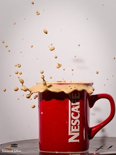 a red coffee mug filled with liquid on top of a table