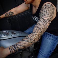 a man with a tattoo on his arm riding a motorcycle