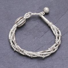 Four strands of 950 silver beads in complementary but varying patterns are twisted together to make this bracelet from Thailand's Pakaon Sojintarit. Where the ends meet a silver hook clasp is accented by a hand-stamped silver ball charm. Areas of oxidization add to the textural beauty of this piece. Karen hill tribe silver is made using techniques that have been passed down through families for generations in Thailand using only hand tools. Bohemian Sterling Silver Beaded Bracelets With Spacer Beads, Silver Multi-strand Jewelry With Spacer Beads, Artisan Silver Bracelet With Polished Beads, Bohemian Bracelets With Sterling Silver Clasp And Round Beads, Elegant Silver Braided Bracelets With Round Beads, Traditional Silver Beaded Bracelets With Spacer Beads, Unique Hand-strung Silver Bracelets, Silver Bohemian Bracelet With Spacer Beads, Silver Multi-strand Bohemian Beads