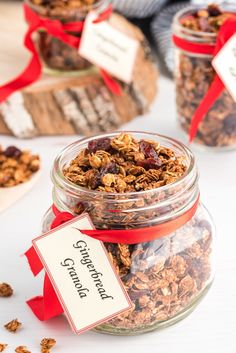 some granola in a glass jar with a red ribbon around it and tags on the top