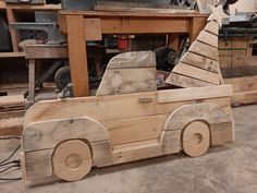 a wooden toy truck with a christmas tree on the back in a workshop area next to other woodworking tools