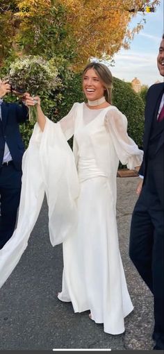 a woman in a white dress is walking with two men