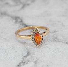 an orange and white diamond ring sitting on top of a marble surface