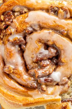 a cinnamon roll with icing and nuts on it sitting on top of some bread