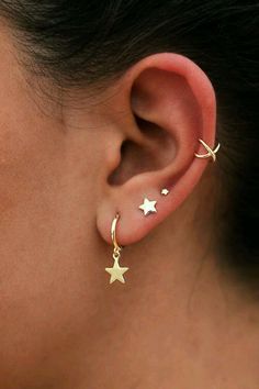 a close up of a person wearing gold ear piercings with stars on the side