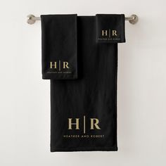 two black towels hanging on the wall with gold foiled letters that read h & r