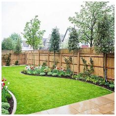 a backyard with green grass and flowers in the center, surrounded by a wooden fence