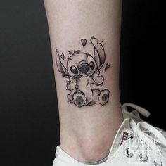 a small tattoo on the ankle of a person with a koala bear and hearts