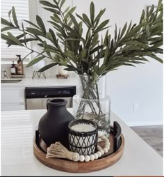 there is a vase with some plants in it on the counter next to a candle holder