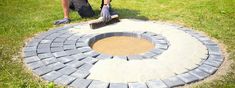 a man is using a broom to clean a circular brick fire pit in the grass