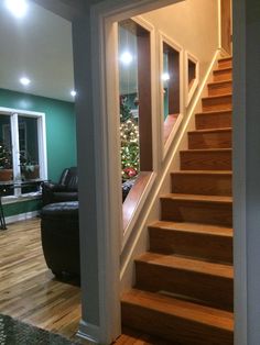 there is a stair case in the living room with christmas tree on the far wall