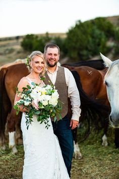 a bride and groom standing in front of horses