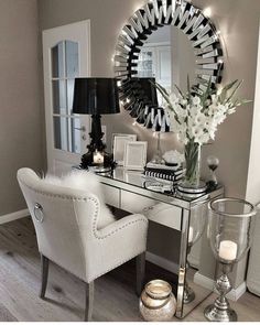 a white chair sitting next to a desk with a mirror on top of it and a vase filled with flowers