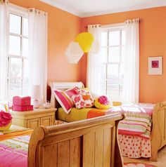 a bedroom with orange walls and pink bedspreads, white curtains, and windows