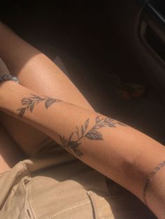 a woman's legs with tattoos on them sitting in the back seat of a car