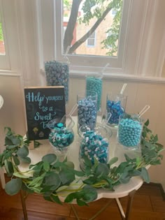 a table topped with lots of candy covered in blue and white candies next to a sign