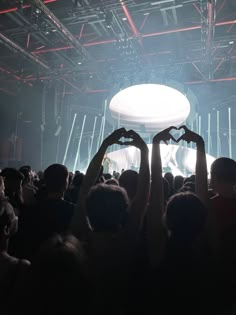 two hands making the shape of a heart in front of a crowd at a concert