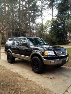 a black suv parked in front of some trees