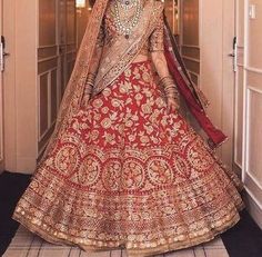 a woman in a red and gold bridal gown is standing on the hallway way