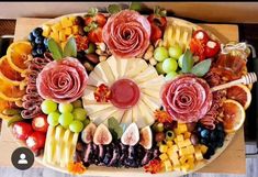 a platter filled with lots of different types of fruits and vegetables on top of a wooden table