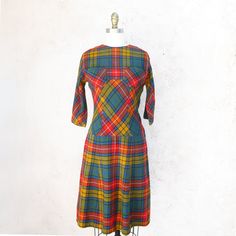 !950's brightly colored wool plaid fit and flare dress in orange, gold, green and black. Fitted at the waist, the bias skirt starts low. It has 3/4 raglan sleeves, a side zipper and 3 covered buttons at the back. There are two breastpockets. It is unlined and has raglan sleeves. Great autumn dress! Fits up to a current size 2 Measurements with room for comfort: Bust up to: 31 inches. Waist up to: 26 inches Hips up to: 37 inches Exact measurements taken flat to compare to a garment which fits wel Fitted Vintage Plaid Dress, Vintage Plaid A-line Dress, Fitted Plaid Retro Vintage Dress, Fitted Retro Plaid Vintage Dress, Retro Plaid Fitted Vintage Dress, Fitted Plaid Vintage Dress, Vintage A-line Plaid Dress, Retro Plaid Mini Dress, Vintage Lined Plaid Dress