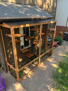 a chicken coop in front of a house next to a purple lawn chair and tree