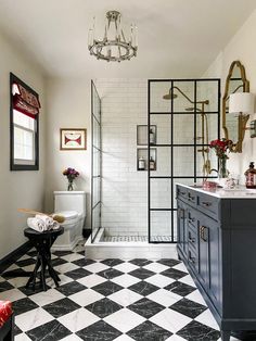 a bathroom with black and white checkered flooring, chandelier above the shower