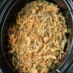 a crock pot filled with green beans and onions