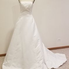 a white wedding dress on display against a wall