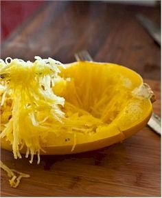 a peeled orange sitting on top of a wooden cutting board next to a knife and fork