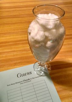 a glass filled with cotton sitting on top of a table next to a piece of paper