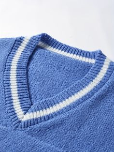 a blue sweater with white stripes on the front and back, sitting on a white surface