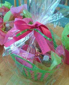 a basket filled with lots of candy sitting on top of a wooden table covered in plastic wrap