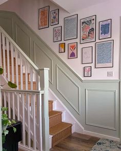 a staircase with pictures on the wall and carpeted stairs leading up to an upstairs landing