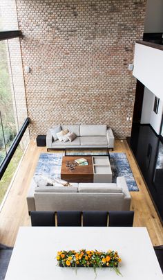 an aerial view of a living room with couches, coffee table and large windows