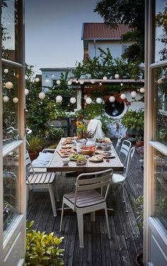 an outdoor dining area with table, chairs and potted plants on wooden decking