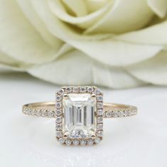 an engagement ring with a white rose in the background