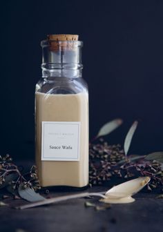 a bottle filled with liquid sitting on top of a table next to dried flowers and leaves