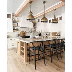 a kitchen with an island and several stools next to the counter top in front of it