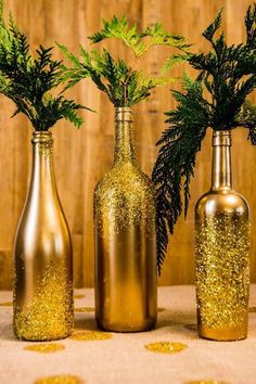 three bottles with plants in them sitting on a table