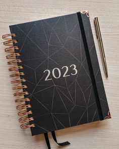 a black notebook with the year 2013 on it and a pen sitting next to it