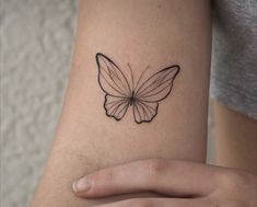 a woman's arm with a small butterfly tattoo on the back of her arm