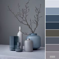 three vases with different shades of blue and grey on top of a white table