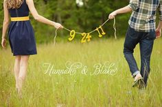 two people holding hands with the numbers twenty and thirteen on them in front of some tall grass