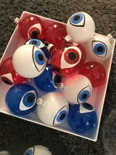 red, white and blue ornaments are in a box on the floor next to each other