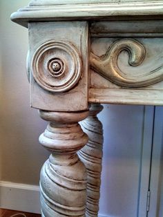 an old wooden table with carvings on the top and bottom, sitting in front of a door